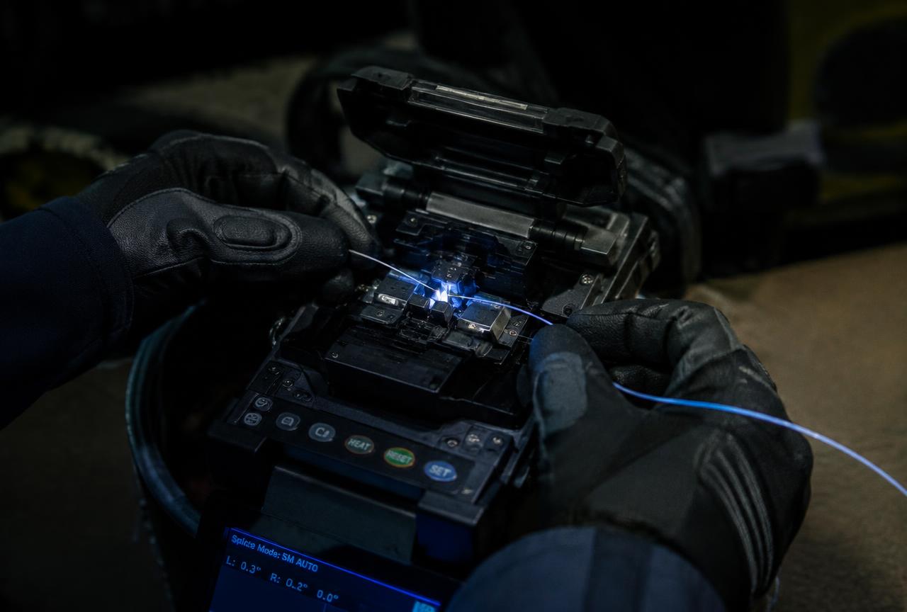 Fiber optic strands being fusion spliced by a technician
